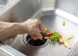 A person puts leftover food through their kitchen sink's garbage disposal