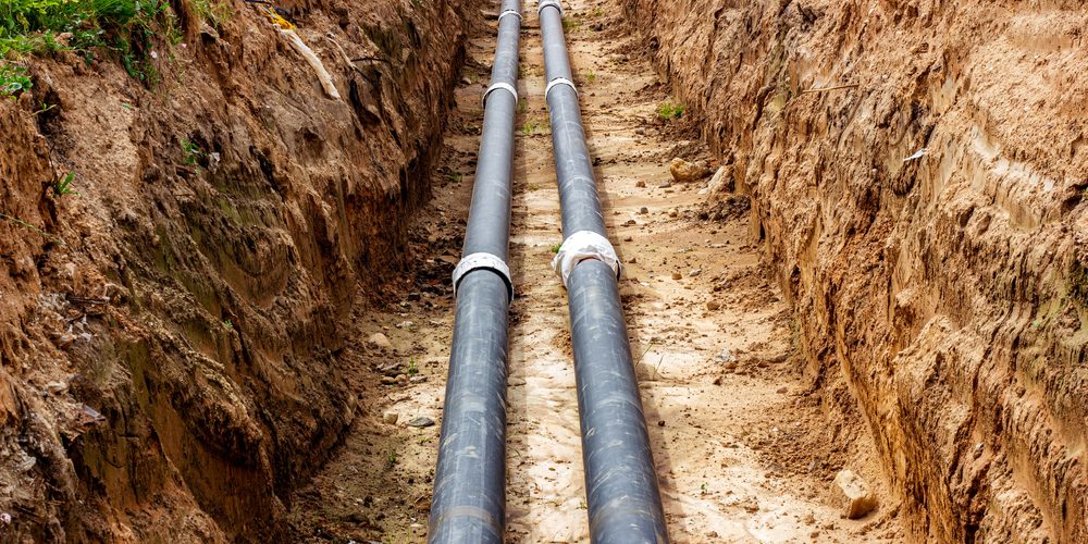 Installation,Of,The,Distribution,Unit,Of,Heating,And,Water,Supply A dug up sewer line with two black pipes