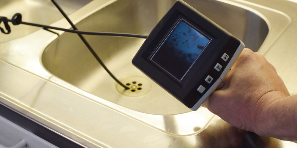 A person uses a camera to check on the status of their drain pipes