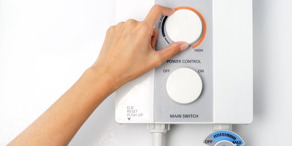 A woman turns the dial on her tankless water heater
