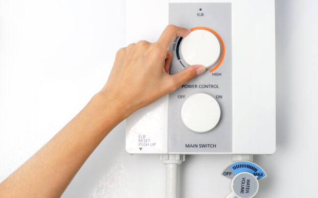 Hand,Rotate,Temperature,Adjuster,Of,Water,Heater.,Temperature,Of,Water A woman turns the dial on her tankless water heater