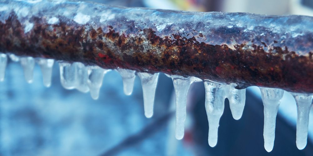 Many,Small,Icicles,Have,Frozen,On,A,Rusty,Pipe,In A closeup shot of a plumbing pipe that has been frozen over