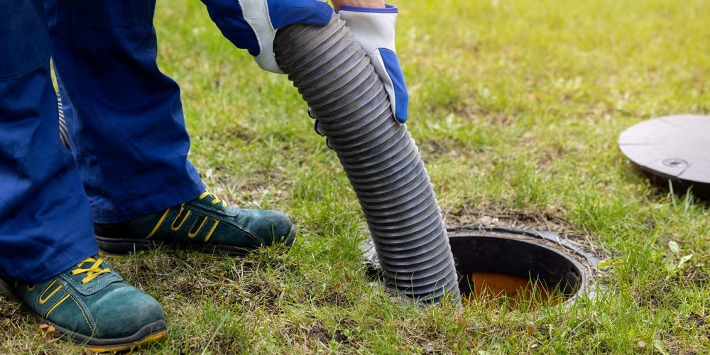 A worker uses a big pipe to clear out a household septic system