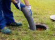 A worker uses a big pipe to clear out a household septic system