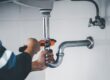 A plumber using a wrench to tighten a pipe